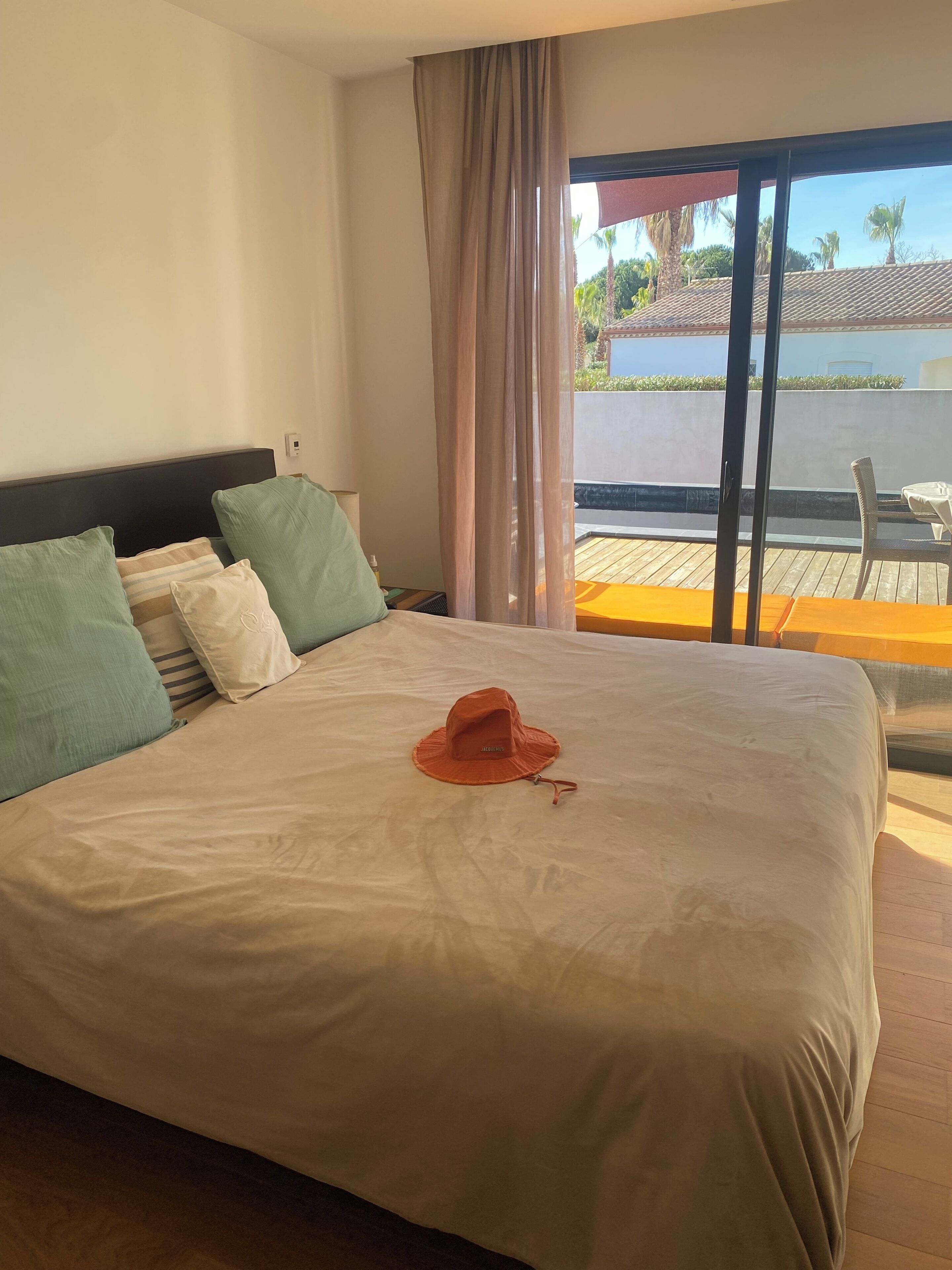 A hotel room with a large bed, a view of the pool, and a balcony with outdoor furniture.
