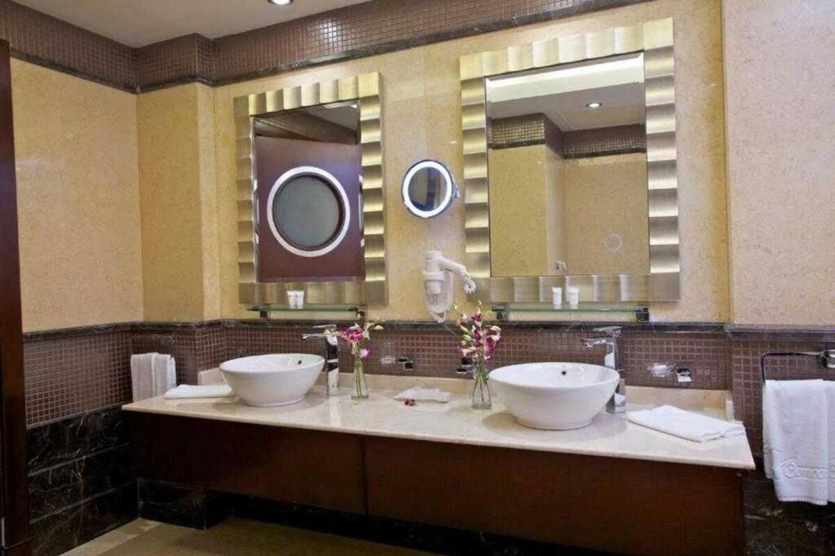 Une salle de bain moderne avec deux grands lavabos, un miroir et des fleurs décoratives.