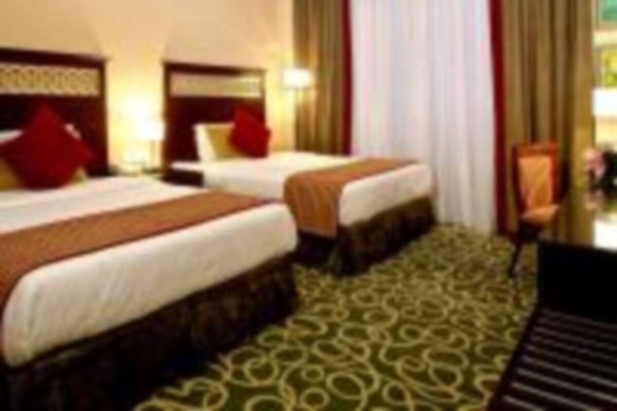 Une chambre d’hôtel avec deux lits, un bureau et une chaise.