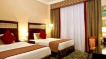 A hotel room with two beds, a desk, and a chair.