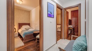 Une chambre à coucher avec un lit en bois, une petite table de chevet et une commode. Il y a une fenêtre donnant sur l’extérieur.