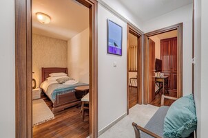 Ein Schlafzimmer mit einem hölzernen Bett, einem kleinen Nachttisch und einem Beistelltisch. Ein Fenster bietet einen Blick ins Freie.