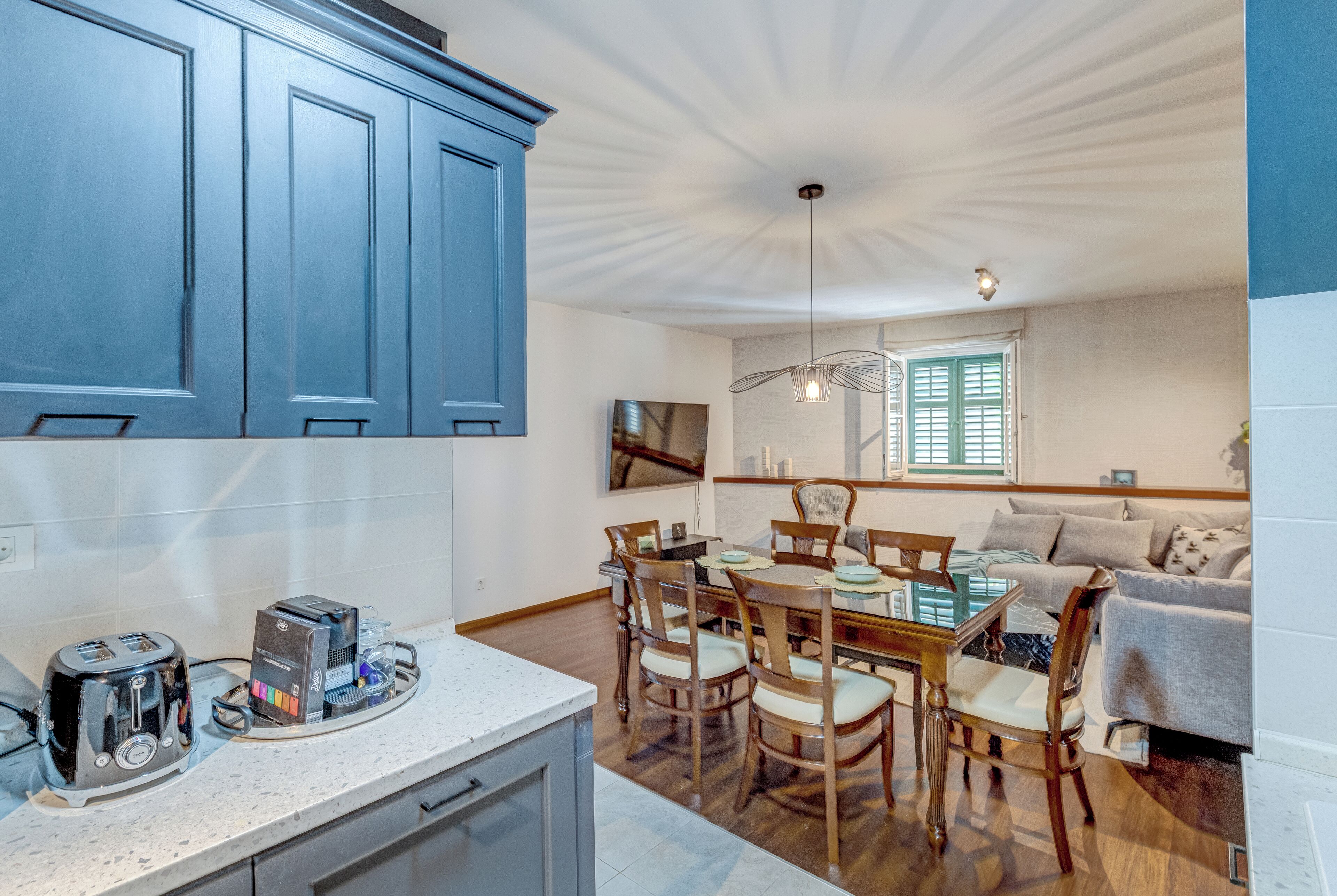 A modern kitchen with a dining area, wooden chairs, and a table.