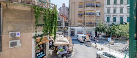 Une vue de rue avec des immeubles, un café et des voitures garées.