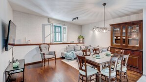 Un coin repas comprenant une table et des chaises en bois, un canapé et un meuble avec des portes en verre.