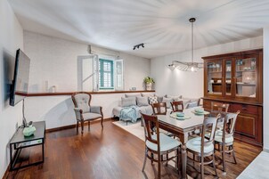 Ein Essbereich mit Holztisch und -stühlen, einer Couch und einem Schrank mit Glastüren.