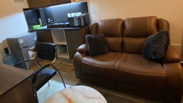 Un salon moderne avec un canapé en cuir, une table à manger et un coin cuisine équipé d’un téléviseur à écran plat et d’appareils électroménagers.