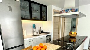Una cocina moderna con una isla de mármol negro, electrodomésticos de acero inoxidable y un cuenco de madera con naranjas.