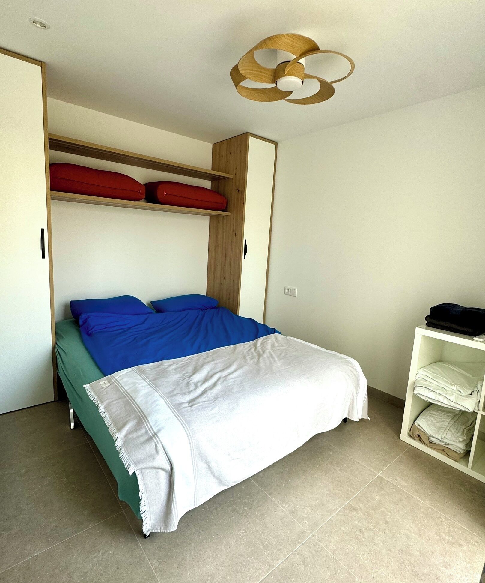 A bedroom with a bed, a wardrobe, and a ceiling fan.