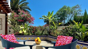 Un patio con dos sillas, una mesa redonda y un frutero.