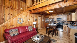A wooden interior with a red leather sofa, a dining table, and a kitchen area.
