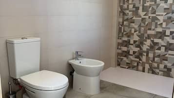 A bathroom with a toilet, bidet, and bathtub.