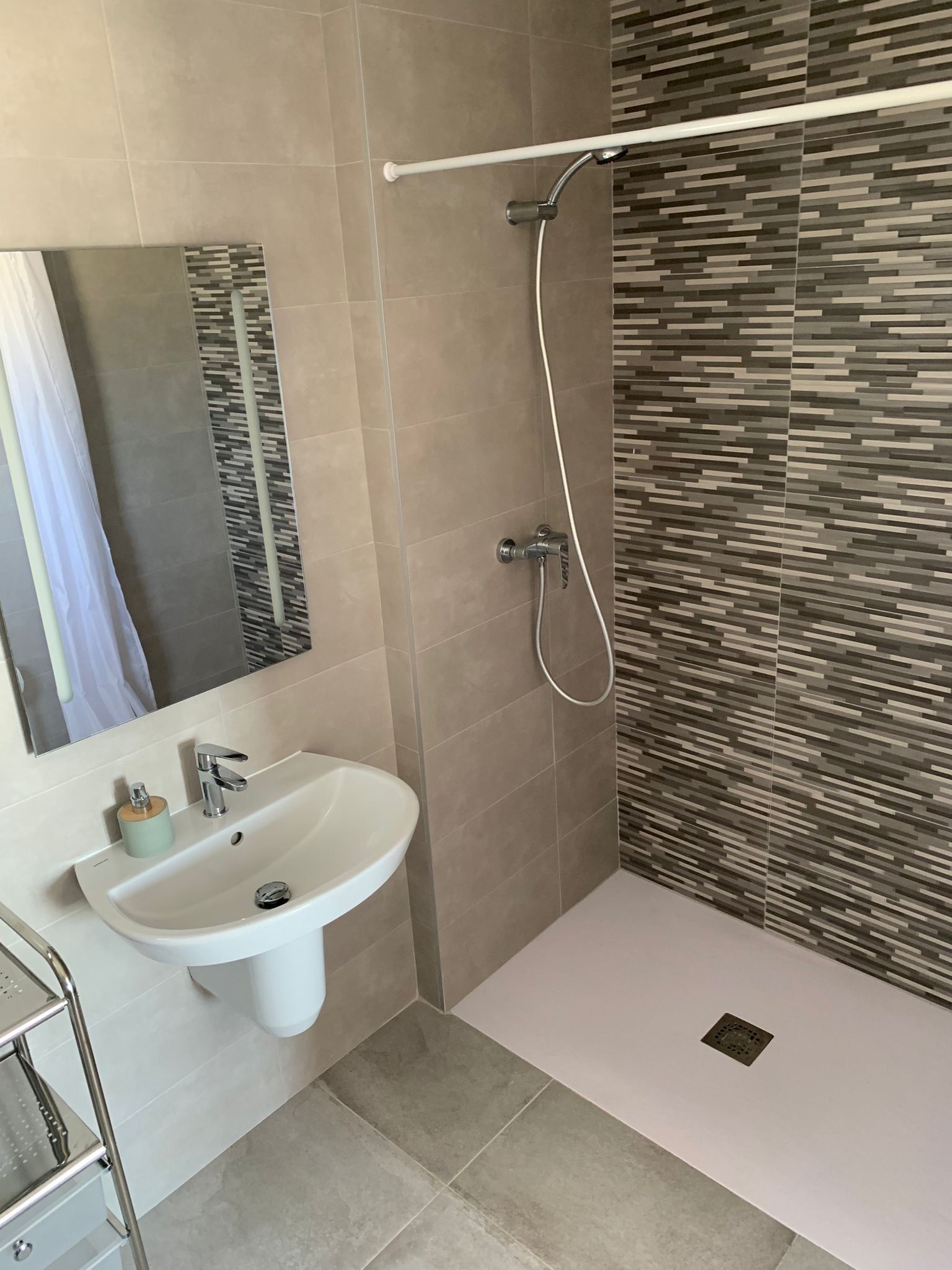 A modern bathroom with a shower, sink, and a mirror.
