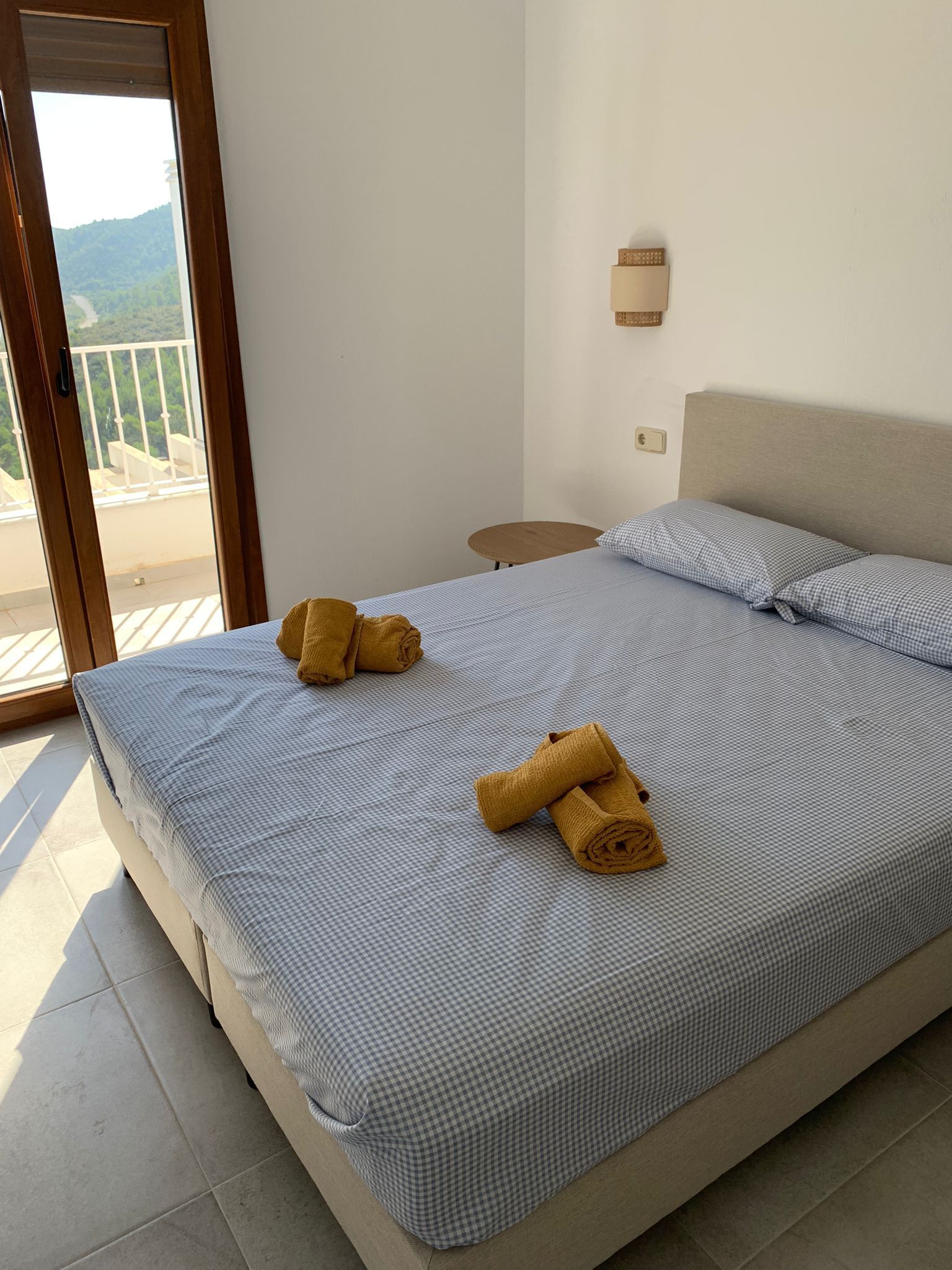 Une chambre avec un lit, une petite table ronde et une vue sur un balcon doté d’une balustrade.