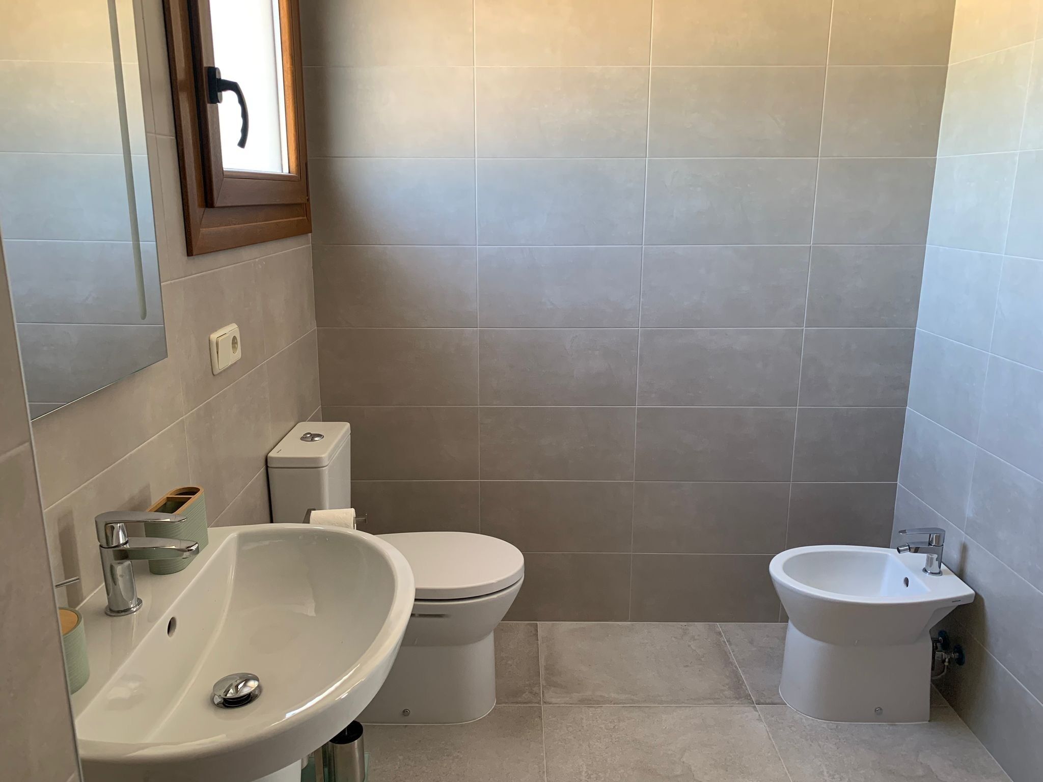 A bathroom with a sink, toilet, and bidet.