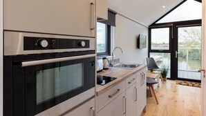 A modern kitchen with stainless steel appliances, a wooden countertop, and a view of the outdoors through a large window. - Tattenhall Marina (Chester)