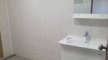 Ein Badezimmer mit weißen Fliesen, einem Waschbecken und einem Spiegel.