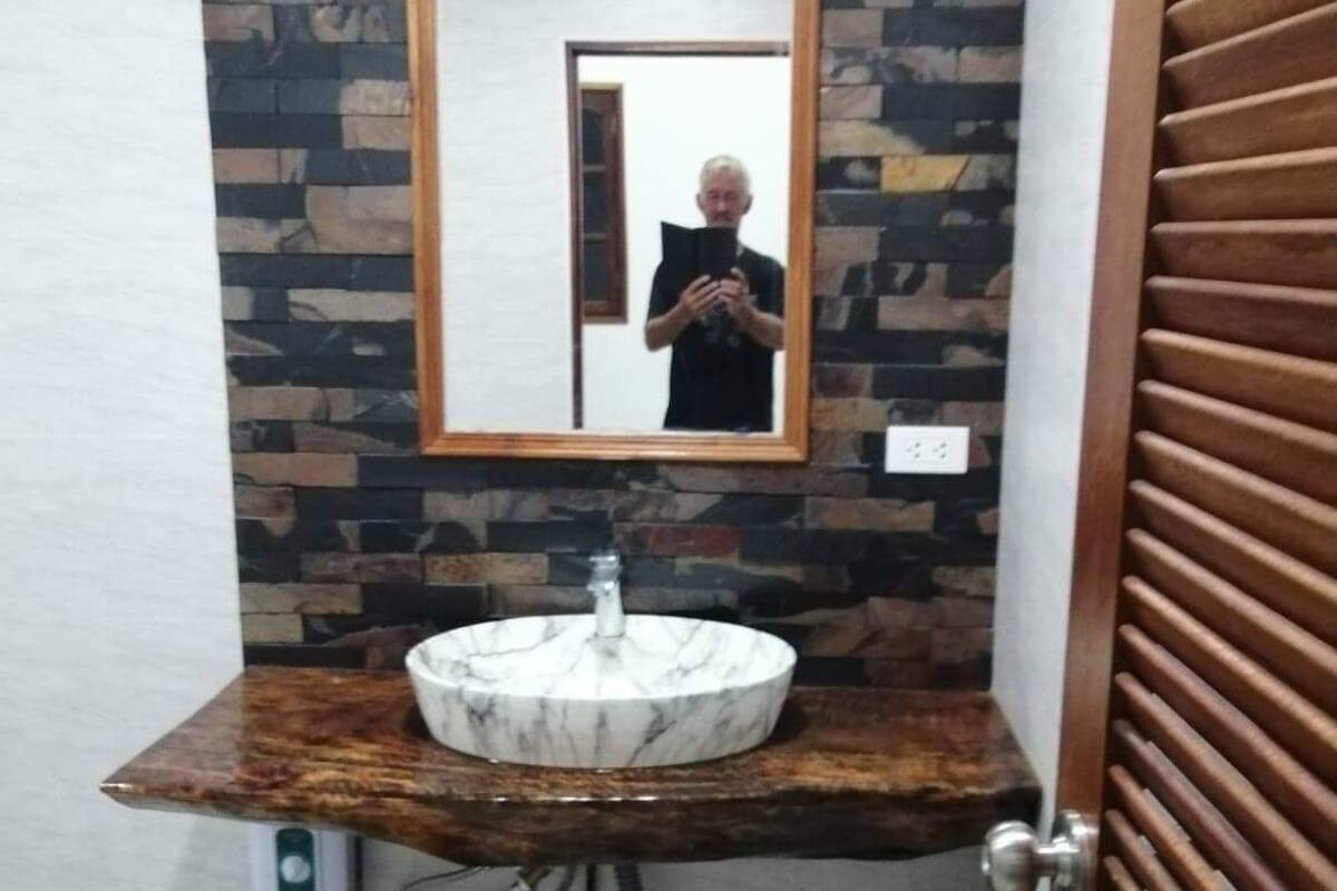 Une salle de bain avec un lavabo en marbre, un meuble-lavabo en bois et un miroir.