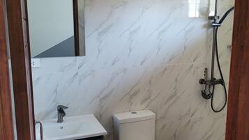 A bathroom with a toilet, sink, and shower.