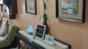 A reception area with a welcome sign, a table with a vase of flowers, and two framed artworks on the wall.