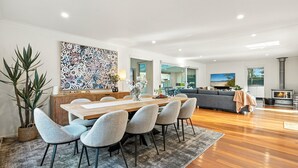 Un espacio habitable moderno con comedor, un cuadro abstracto grande, chimenea y vistas al exterior.
