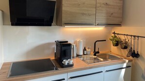 Una cocina moderna con horno integrado, cafetera, hervidor de agua y pileta.