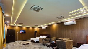 Un vestíbulo de hotel con piso de mármol, una cama, dos sofás, un televisor y un equipo de aire acondicionado.