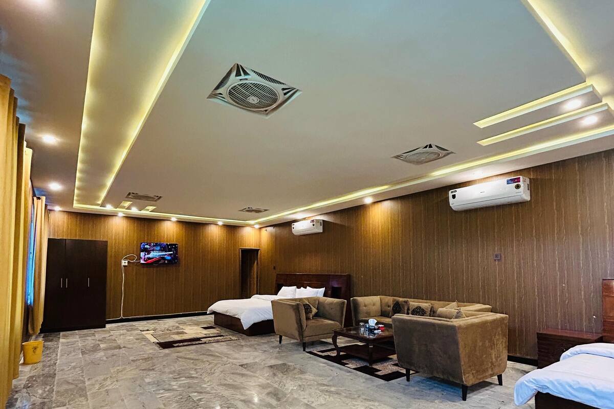 A hotel lobby with a marble floor, a bed, two sofas, a TV, and an air conditioning unit.