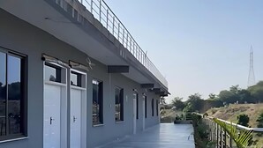 Un edificio moderno con una galería cubierta, ventanas amplias y plantas en macetas.