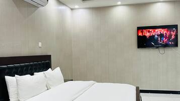 A modern hotel room with a large bed, a flat-screen TV mounted on the wall, and an air conditioning unit on the ceiling.