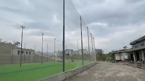 Un campo deportivo con focos, una pista de atletismo verde y un edificio de varios niveles.