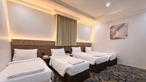 Ein Hotelzimmer mit vier Betten, einem gemusterten Teppich und einer dekorativen Wandverkleidung.