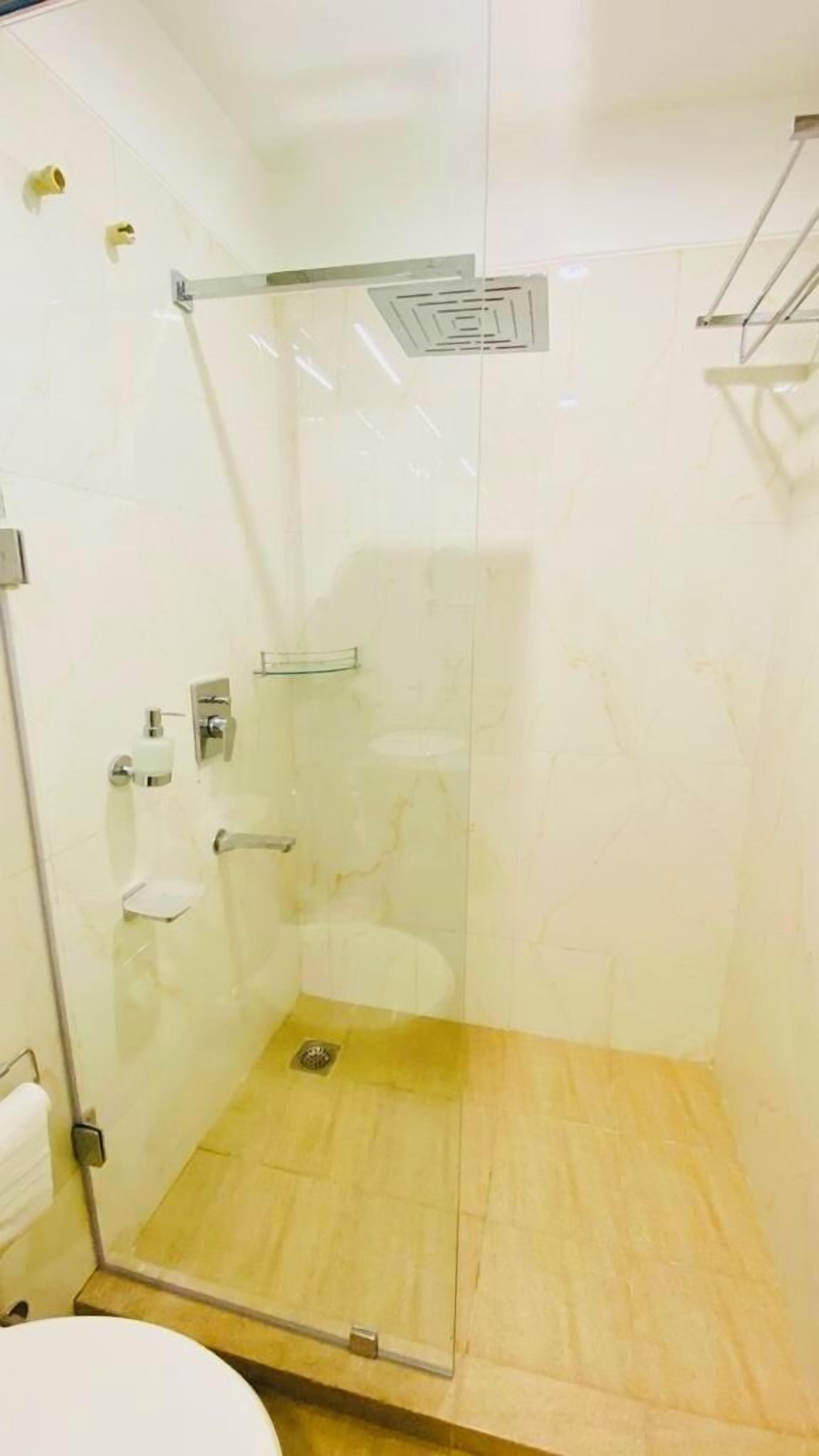 Eine begehbare, gläserne Dusche mit Holzboden, Toilette und Handtuchhalter.