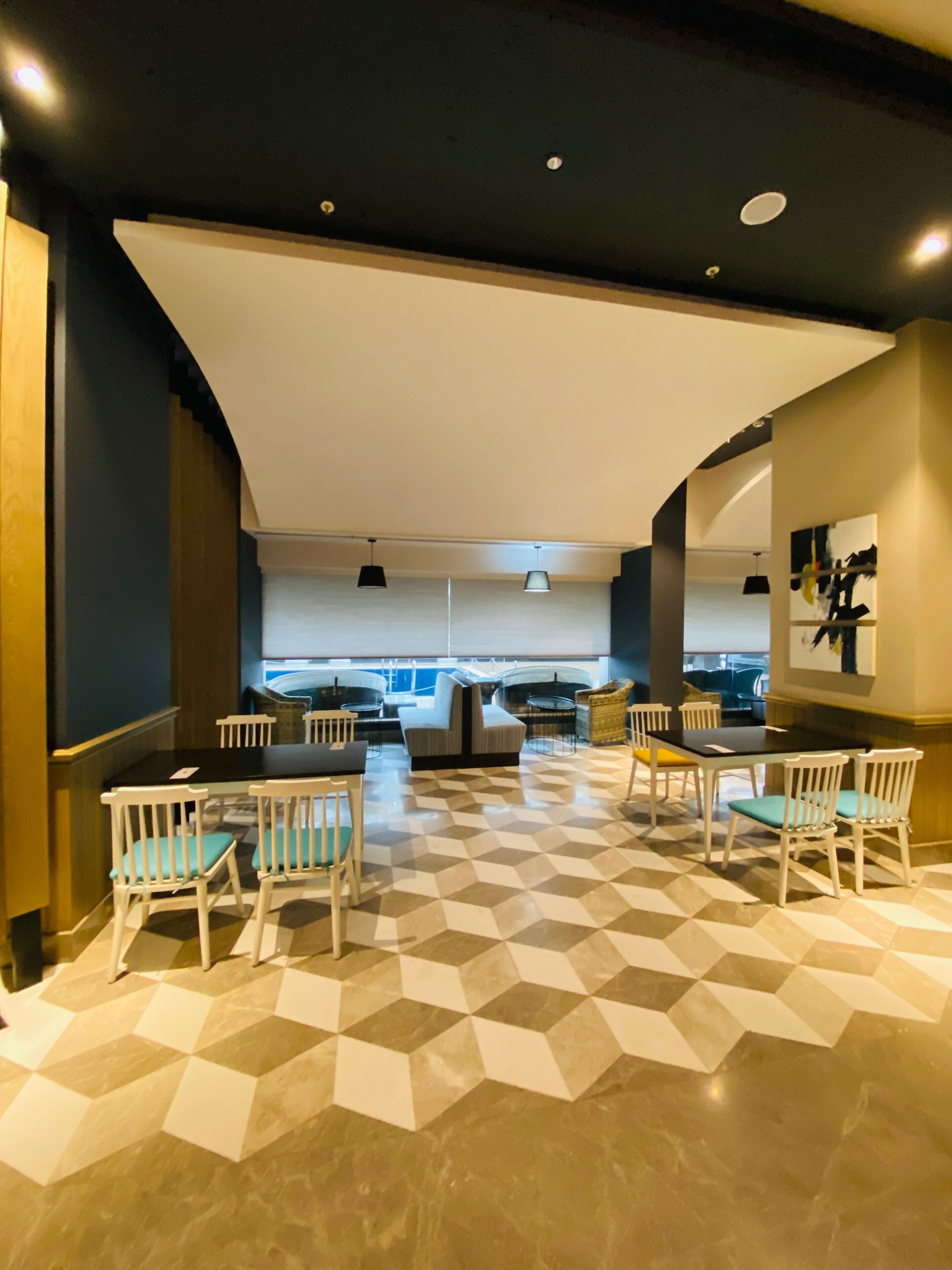 A modern dining area with a geometric patterned floor, white chairs, and a large table.