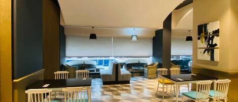 A modern dining area with a geometric patterned floor, white chairs, and a large table.