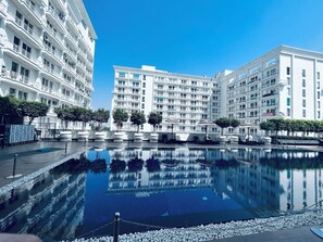 A modern hotel with a central pool, surrounded by white buildings and trees. - MIGROLINO (Lucknow)