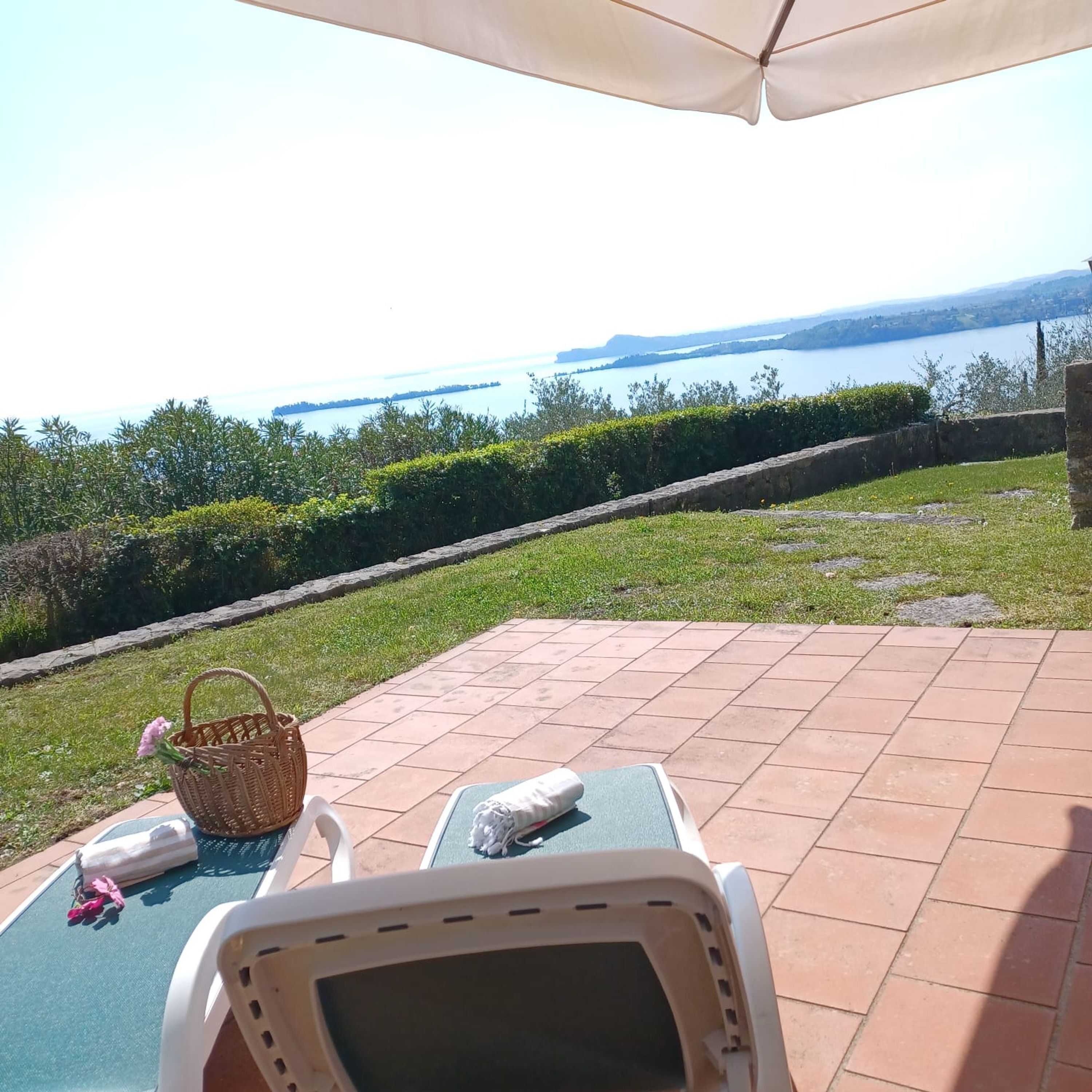 A patio with two lounge chairs, a wicker basket, and a table with a towel and flowers.