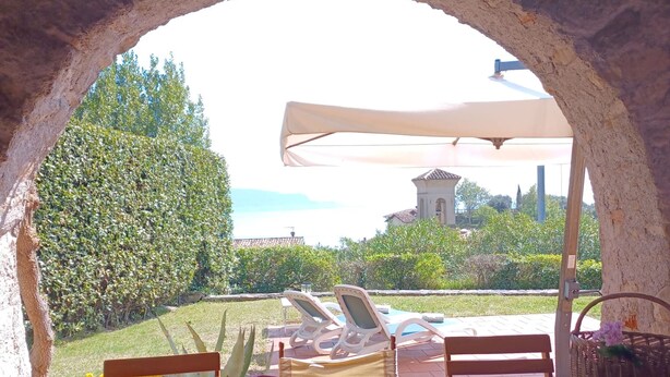 Een terras buiten met een tafel gedekt voor twee personen, een stoel en een parasol.