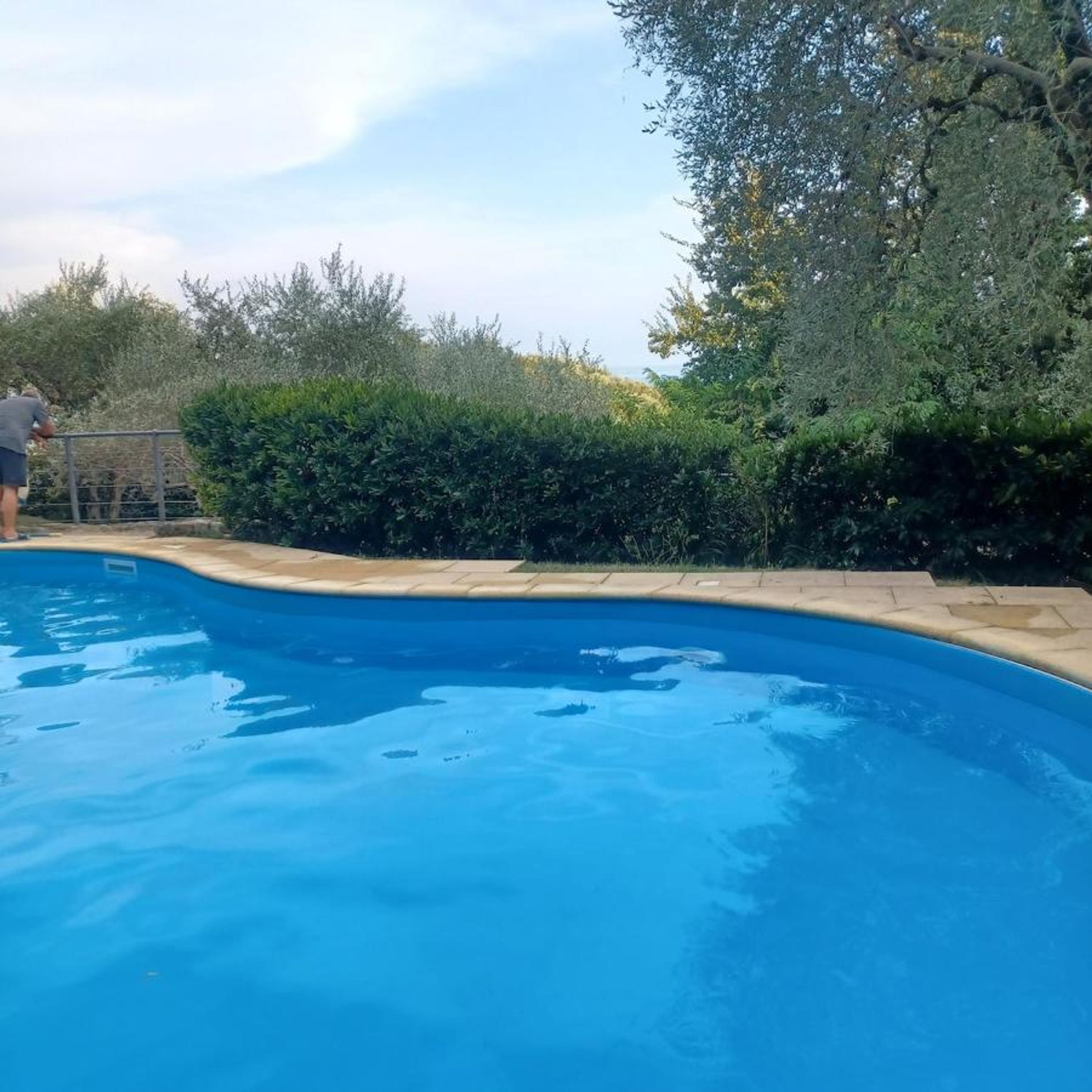 Une piscine avec une personne debout au bord.