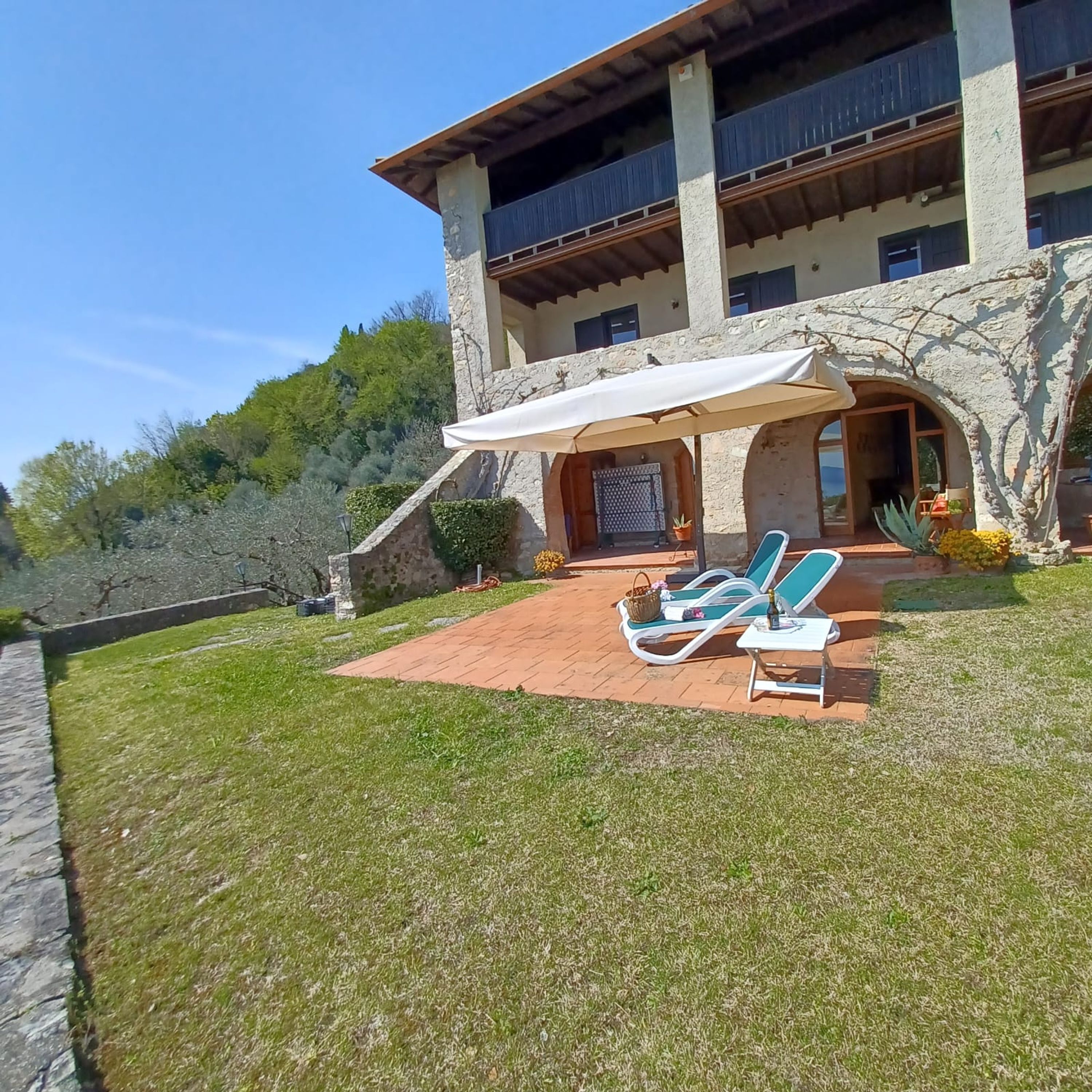 Ein Steinhaus mit überdachter Terrasse, Sitzgelegenheiten im Freien und Blick auf die umliegende Landschaft.