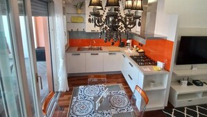 Een moderne keuken met een centraal eiland, een kroonluchter en een eetgedeelte met patroon tegels.