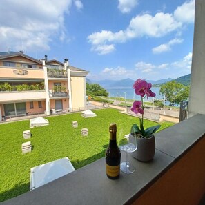 A balcony with a bottle of wine, a glass, and a potted orchid. - Promenade Luxury View (Sarnico)