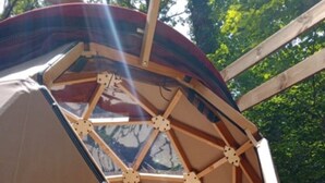 A geodesic dome structure with a triangular window design, surrounded by a wooden deck. - Dodôme étoilé-Love Room (Saint-Germain-d'Esteuil)