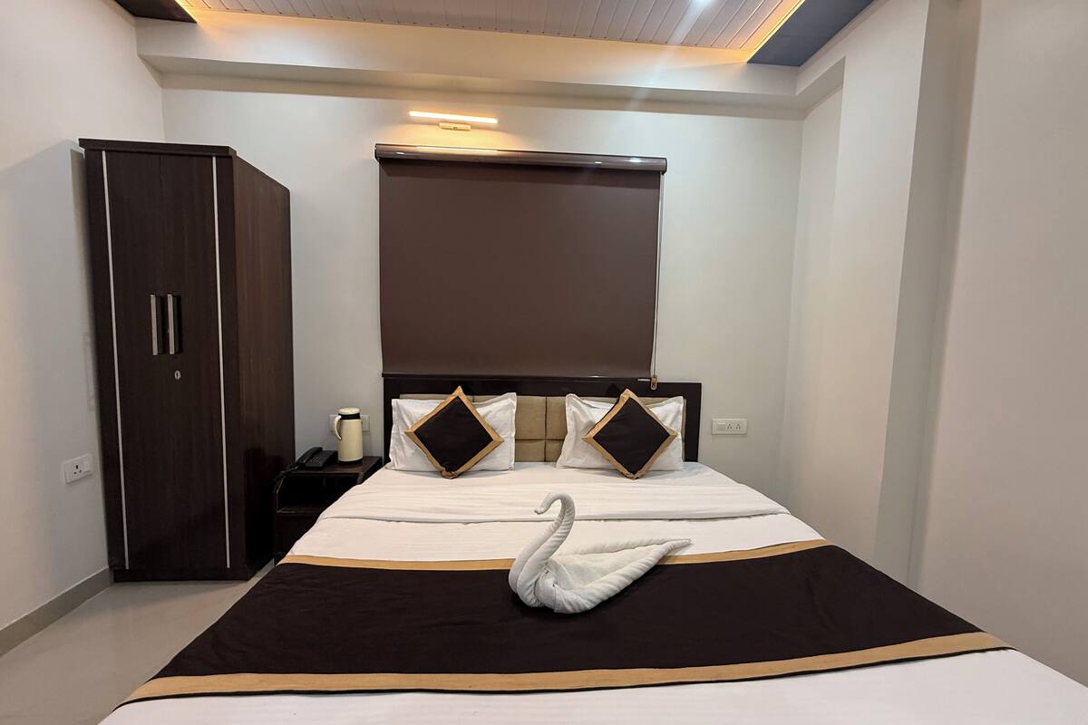A hotel room with a bed, a wardrobe, a bedside table with a lamp, and a ceiling light.
