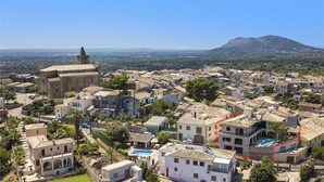 Uma vila costeira com arquitetura tradicional, uma torre imponente e uma montanha ao fundo.