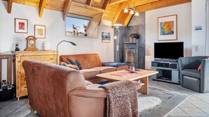 Un salon chaleureux avec un plafond en bois, une cheminée, un téléviseur et un canapé.