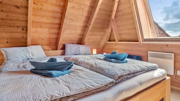 Une pièce de style cabane en bois, avec deux lits, une lucarne et une fenêtre visible.