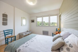 A bedroom with a bed, a desk, a chair, a window, and a radiator.