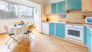 Una cocina moderna con armarios verde azulado, un lavavajillas y un microondas.