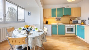 Una cocina moderna con armarios color turquesa, una estufa blanca y una mesa de comedor preparada para cuatro personas.